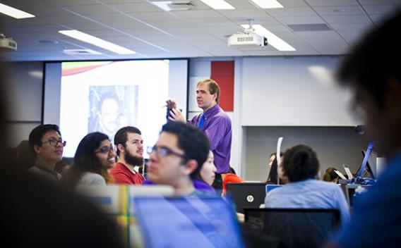 Instructor walking and talking in a classroom.