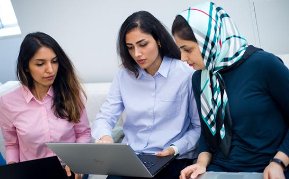 Three woman looking at a laptop.